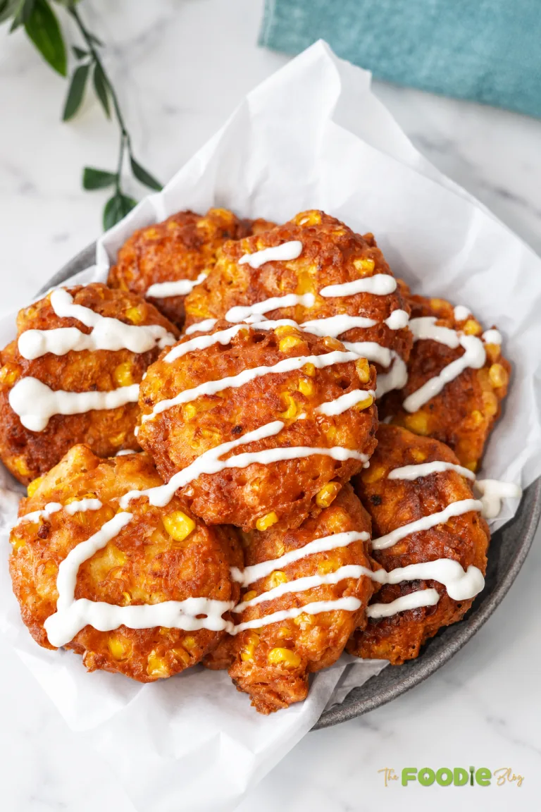 Crispy sweet corn fritters with feta cheese served with a creamy sauce drizzle.