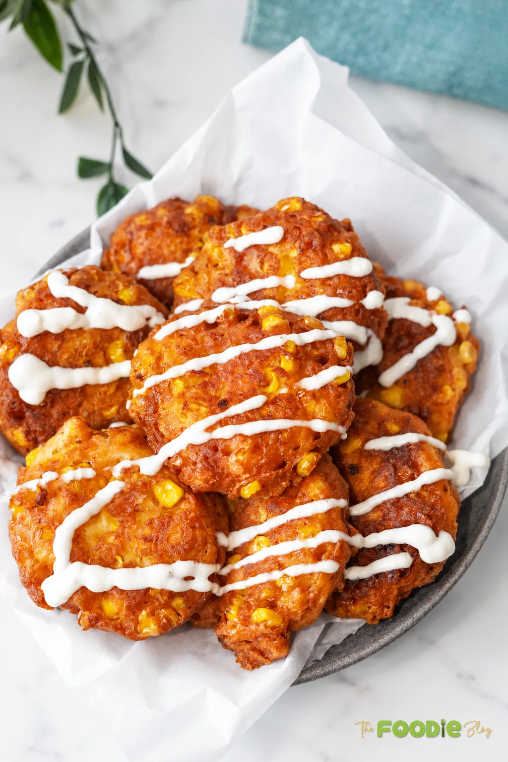 Crispy sweet corn fritters with feta cheese served with a creamy sauce drizzle.