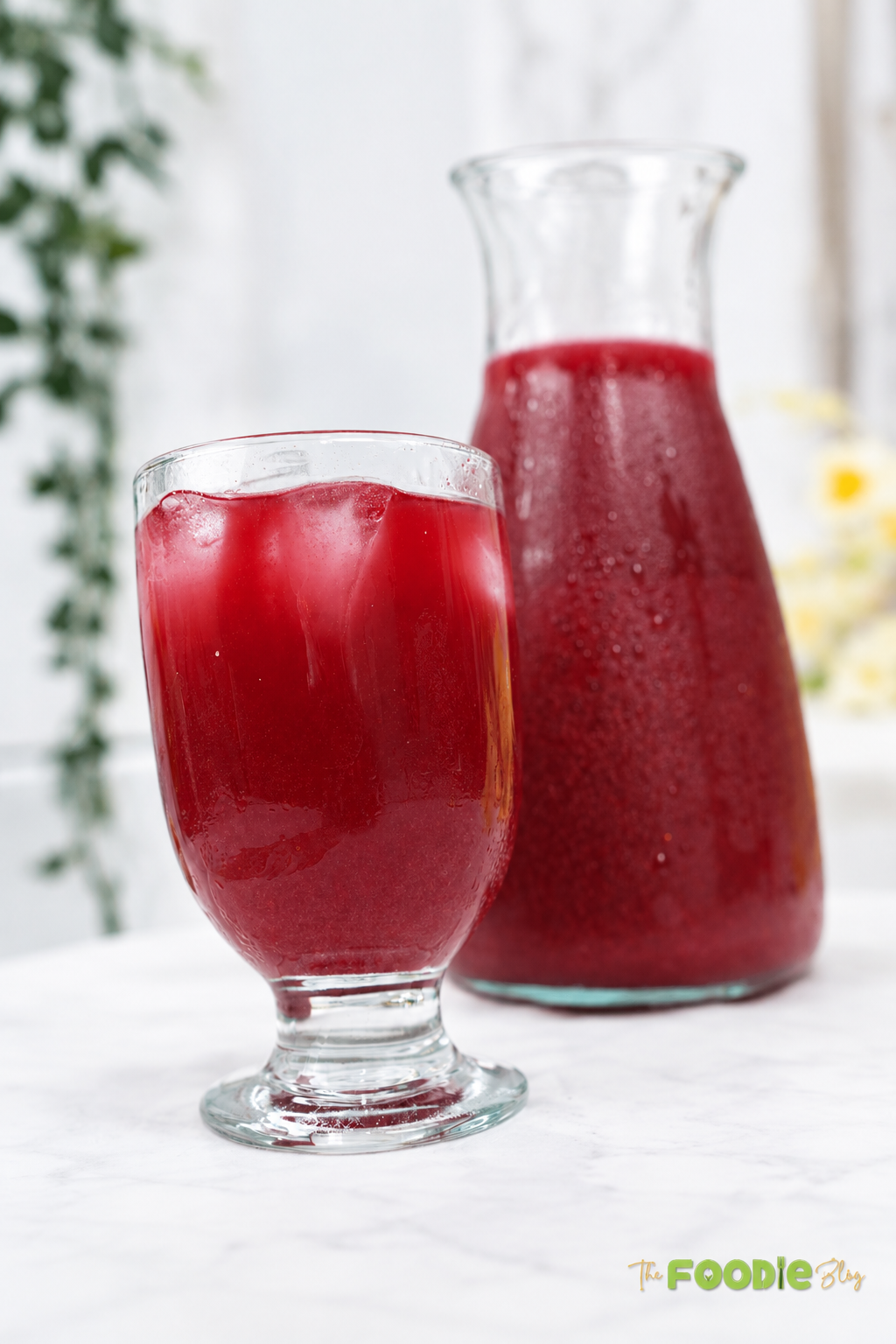 Glass of chilled beetroot juice with ice cubes beside a pitcher of fresh beetroot juice.