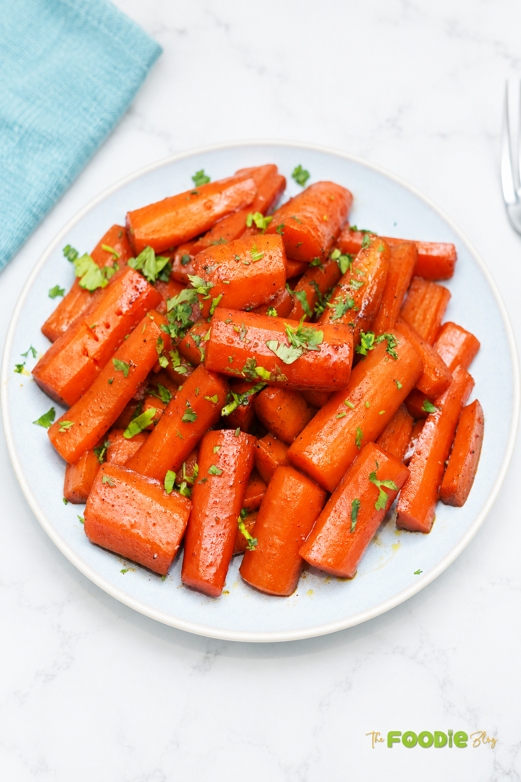 Candied carrots served on a plate with brown sugar cinnamon glaze and fresh parsley.
