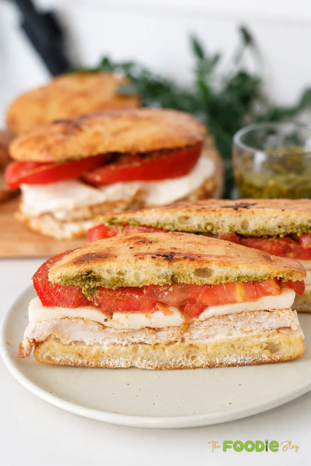 Chicken pesto sandwich cut in half with mozzarella and fresh tomato