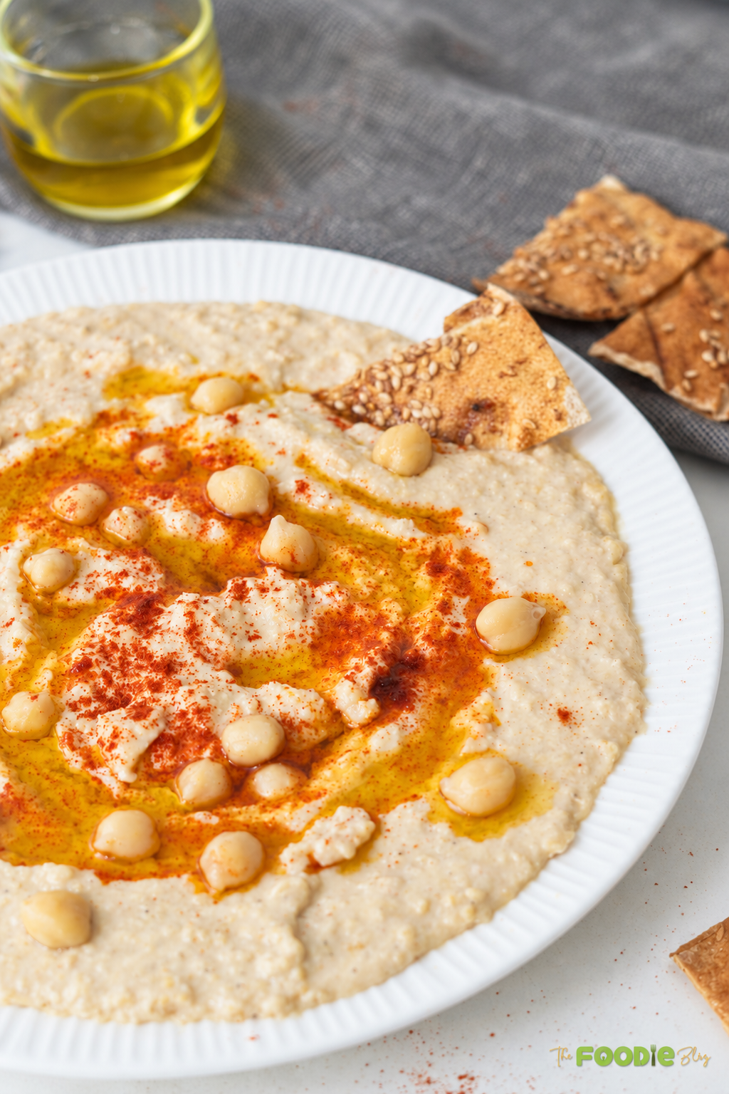 Close-up of creamy hummus with chickpeas, paprika, olive oil, and toasted pita chips
