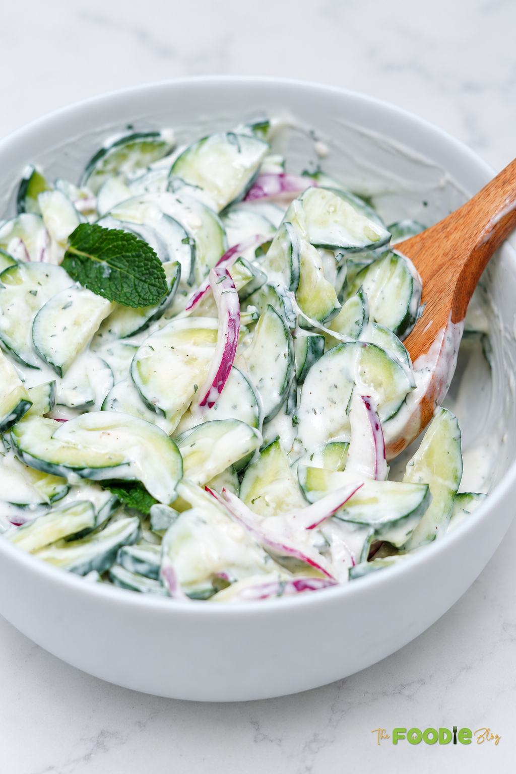 Close-up of creamy cucumber salad with Greek yogurt, mint, and red onion.