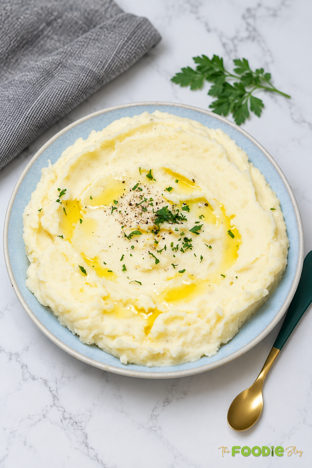 Creamy mashed potatoes served on a plate with butter, parsley, and black pepper.