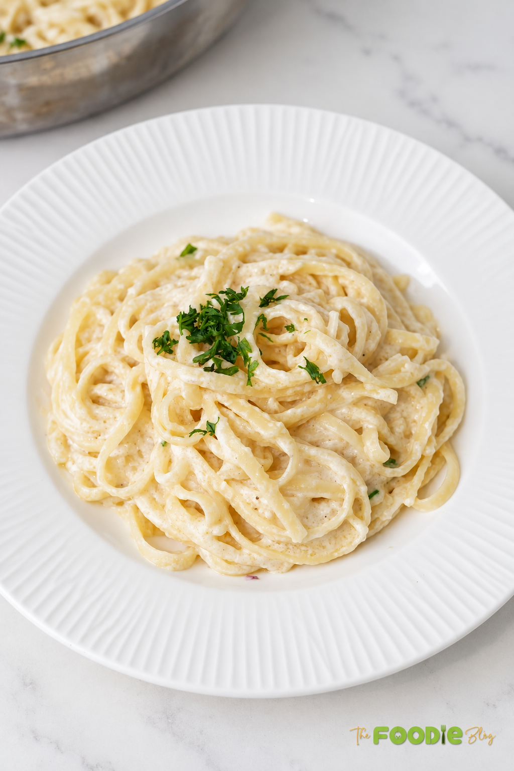 Fettuccine Alfredo served on a white plate with creamy Parmesan sauce and fresh parsley.