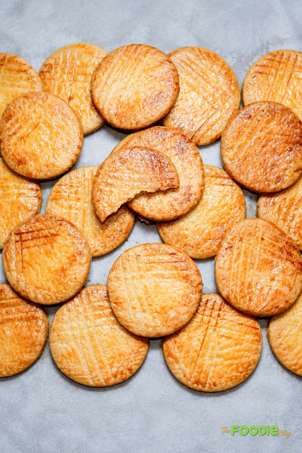 Homemade Galettes Bretonnes arranged on a wooden board with golden tops and traditional fork marks.
