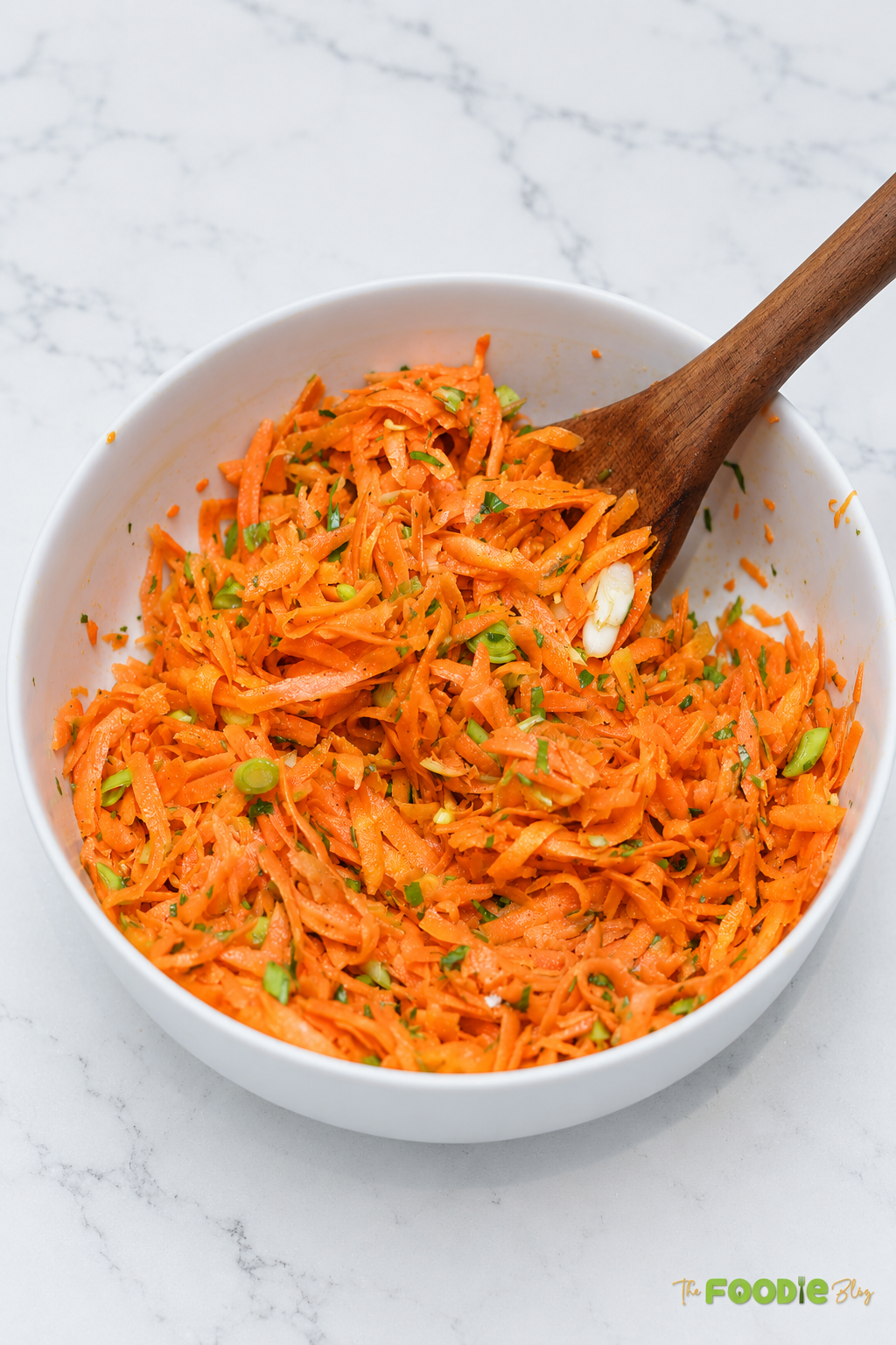 Fork lifting grated carrot salad with green onions and fresh parsley.