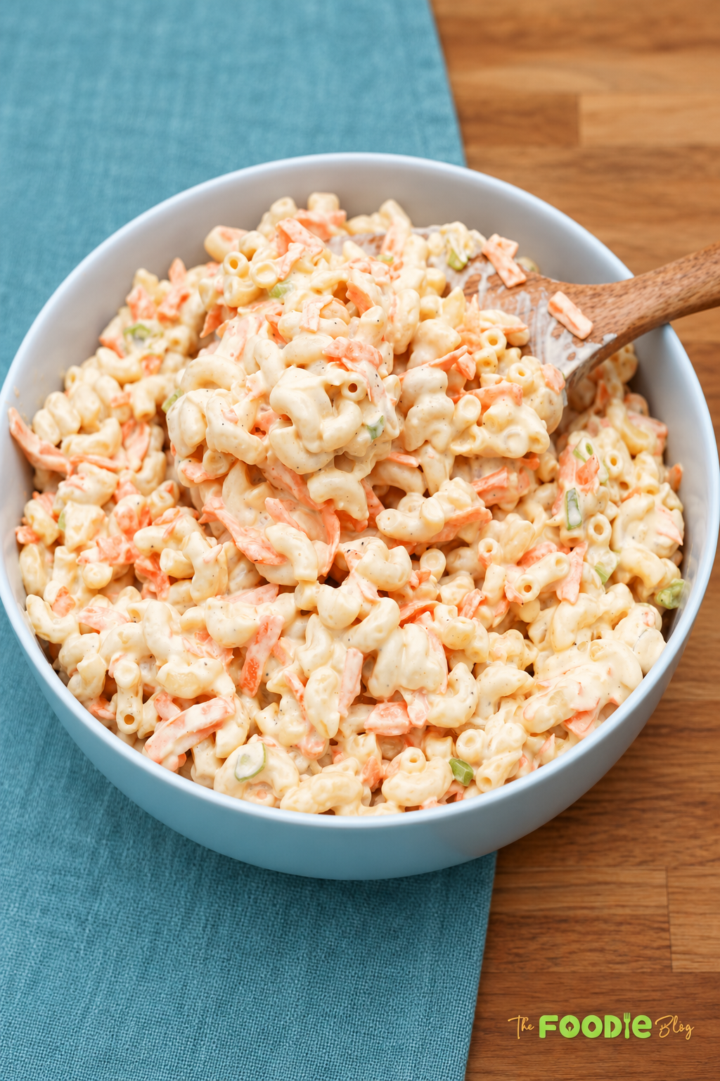 Creamy Hawaiian macaroni salad served in a blue bowl with carrots and green onions.
