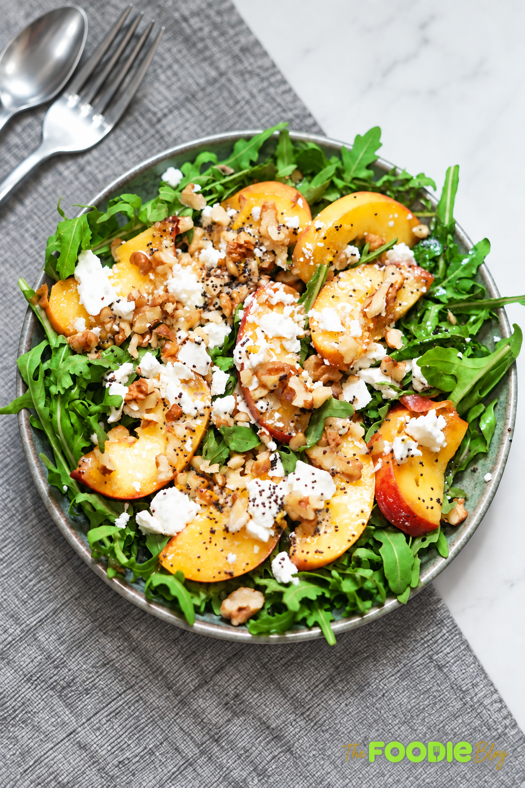 Overhead view of peach arugula salad with feta, walnuts, and poppy seed dressing.