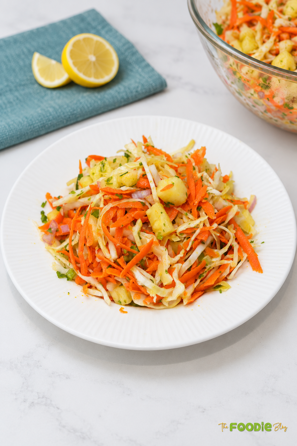 Pineapple coleslaw served on a white plate with shredded cabbage, carrots, pineapple chunks, red onion, and herbs.