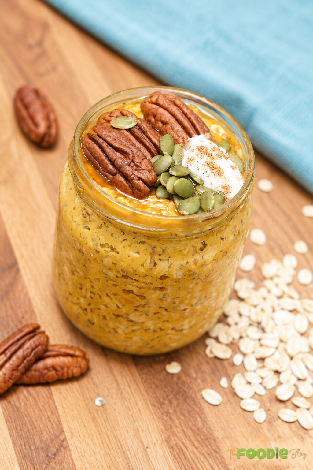 Creamy pumpkin overnight oats with pecans, pumpkin seeds, Greek yogurt, and cinnamon served in a jar.