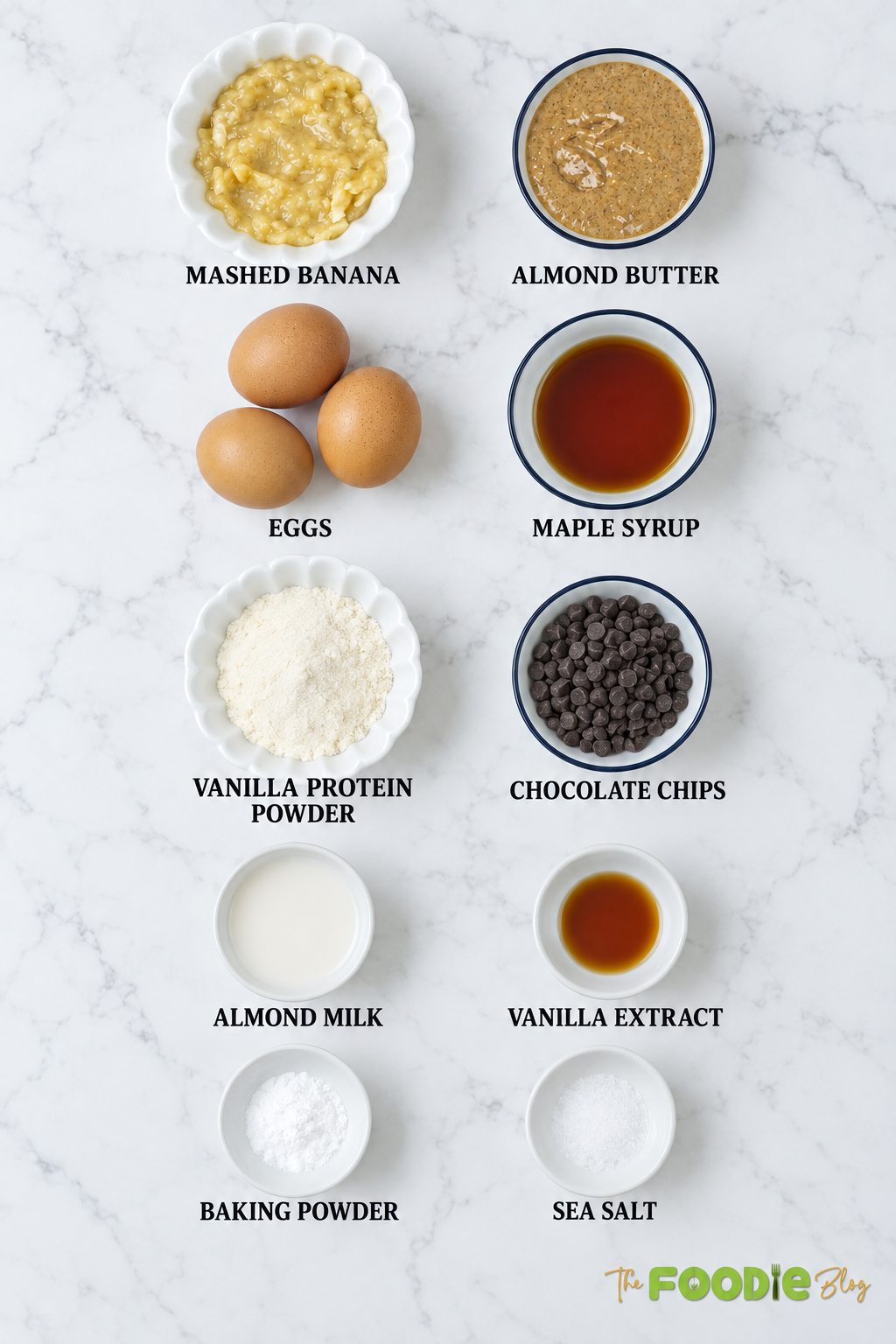 Ingredients for banana protein muffins including mashed banana, almond butter, eggs, maple syrup, protein powder, chocolate chips, almond milk, vanilla, baking powder, and salt.