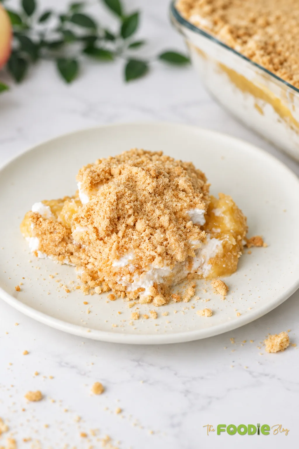 Slice of no-bake peach dessert served on a plate with creamy filling, peach layer, and biscuit crumbs.