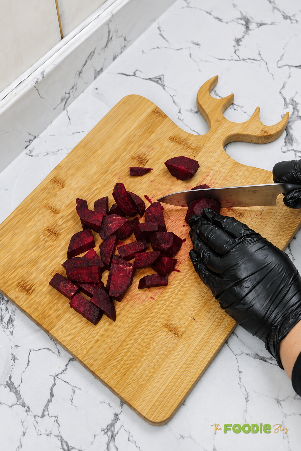 Peeled beetroot being chopped into small pieces on a wooden cutting board.