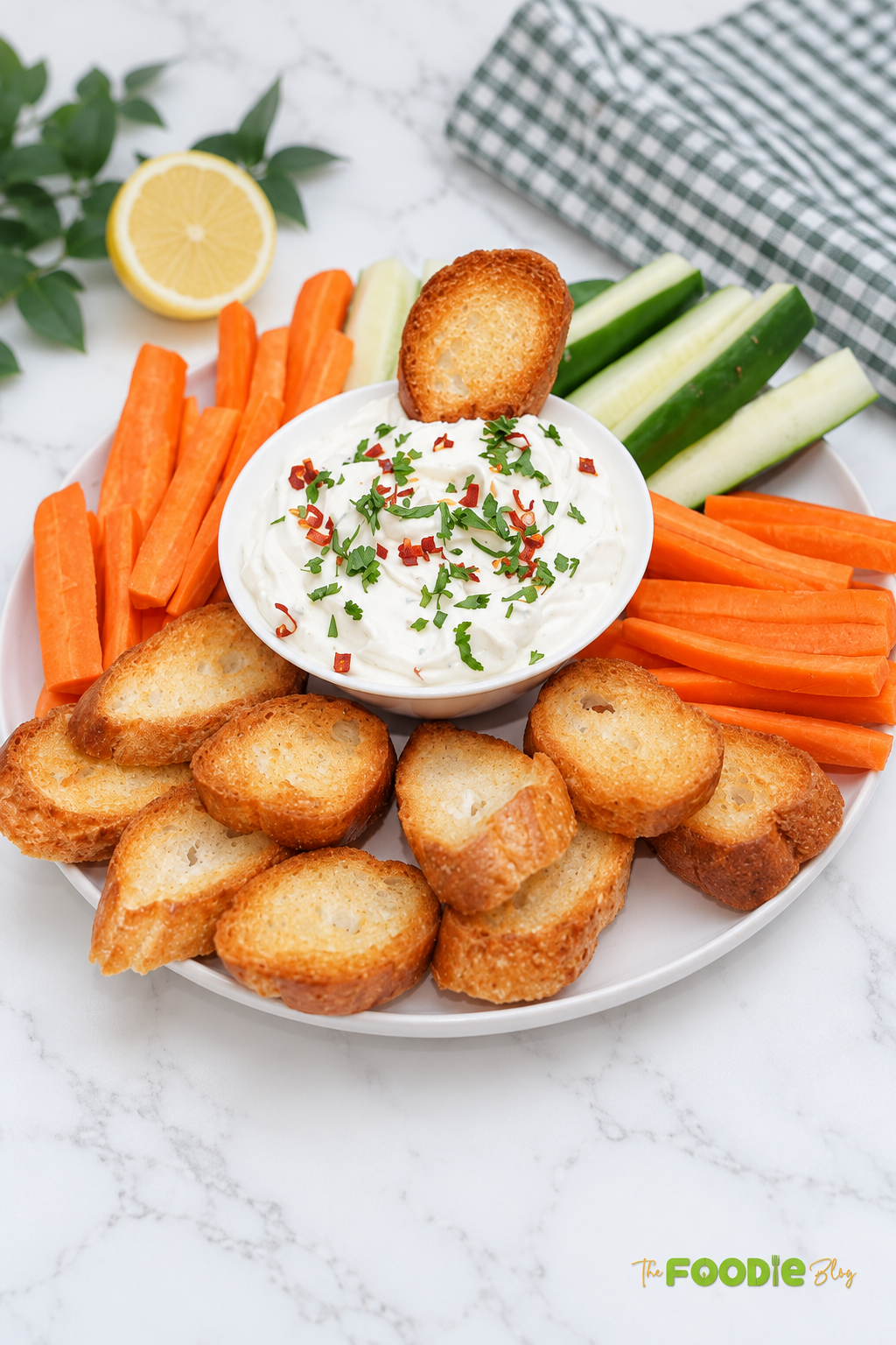 Creamy feta and cream cheese dip topped with herbs and served with carrots, cucumbers, and toasted bread.