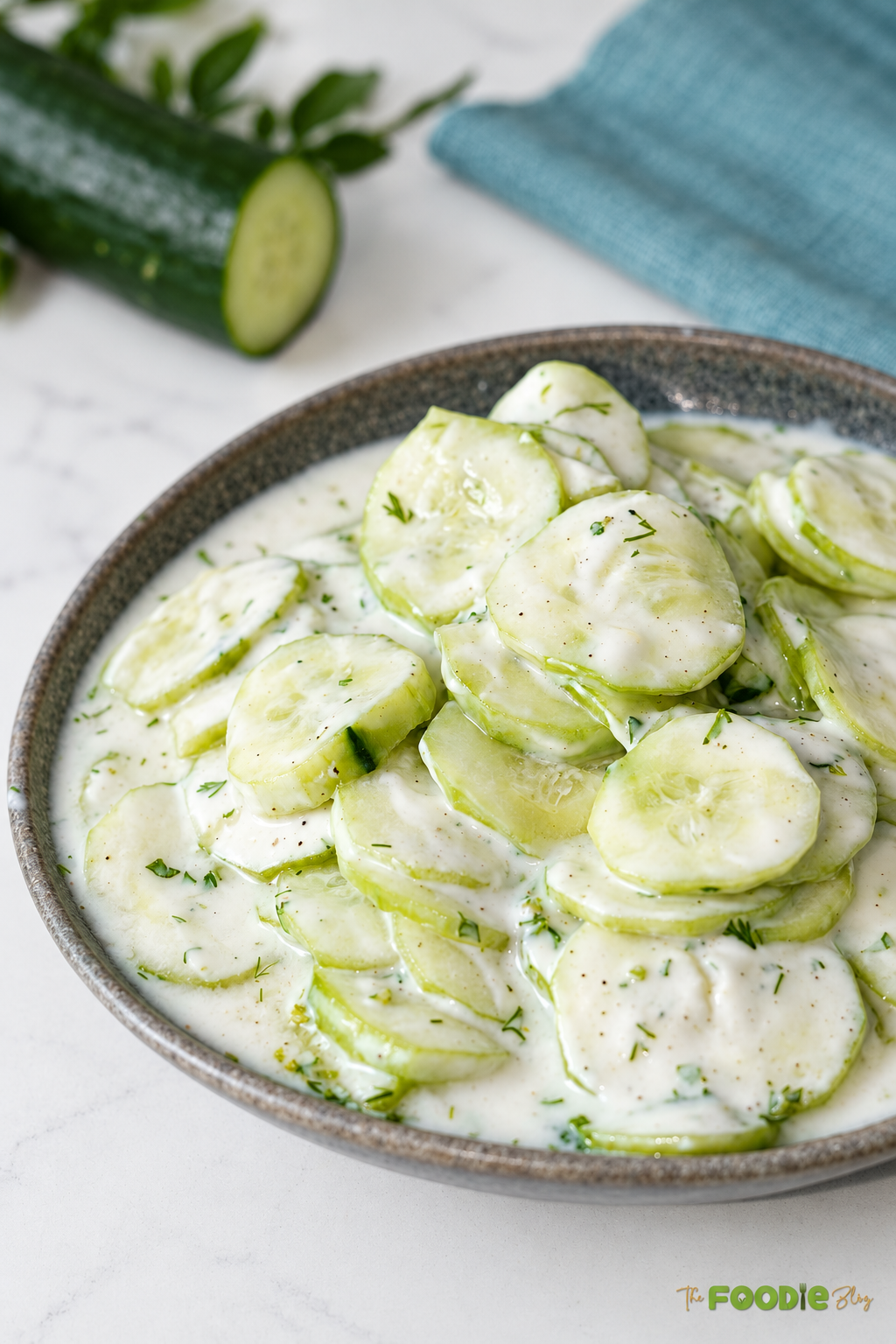 Close-up of creamy German cucumber salad with sliced cucumbers and fresh dill in sour cream dressing.