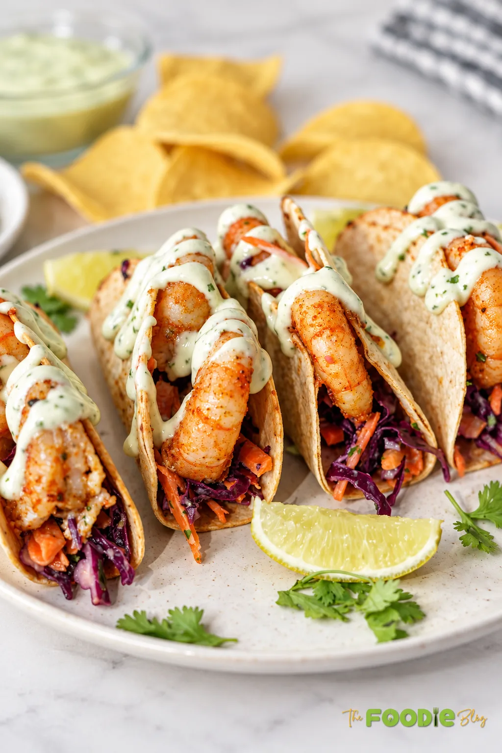 Close-up Mexican shrimp tacos with seasoned shrimp, cabbage slaw, cilantro lime crema, and fresh lime.