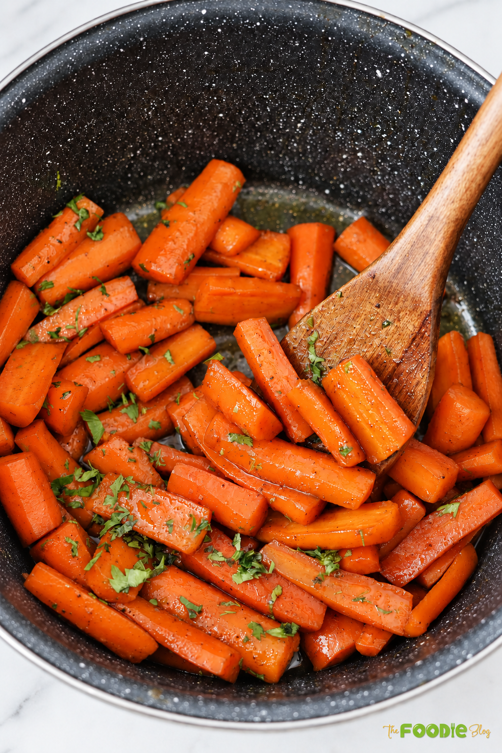 Glazed candied carrots in a pot coated with brown sugar butter sauce and topped with fresh parsley.