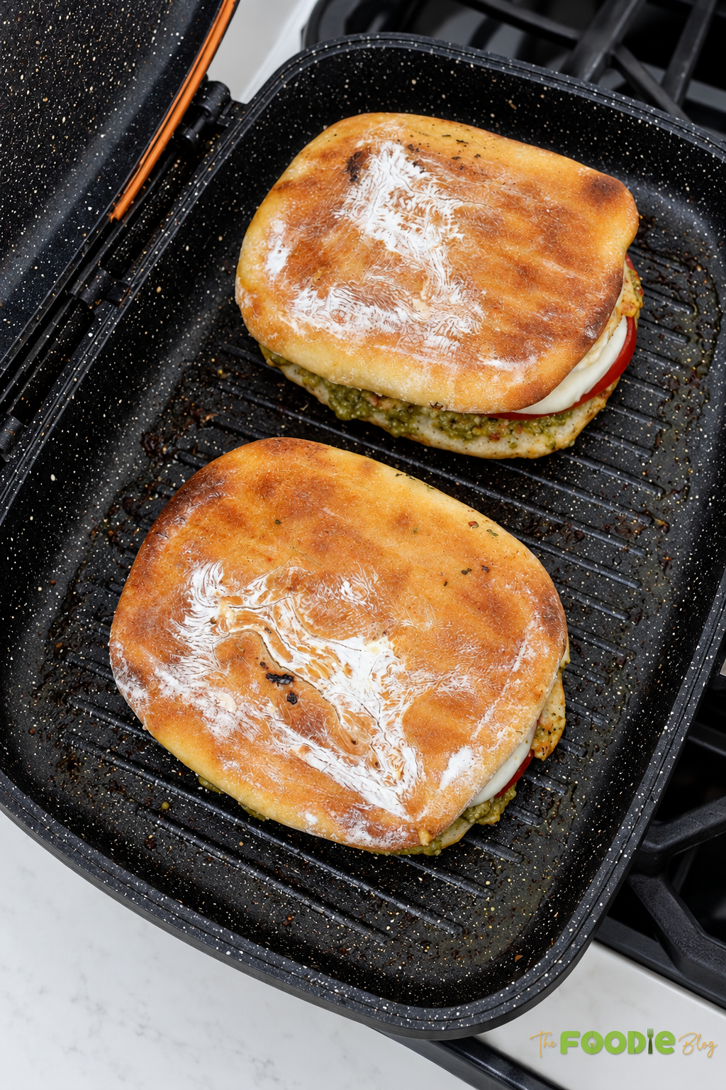 Chicken pesto sandwiches grilling in a pan until golden brown