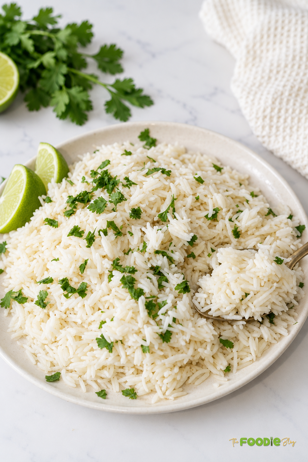 Spoonful of fluffy coconut lime rice garnished with cilantro beside fresh lime wedges.