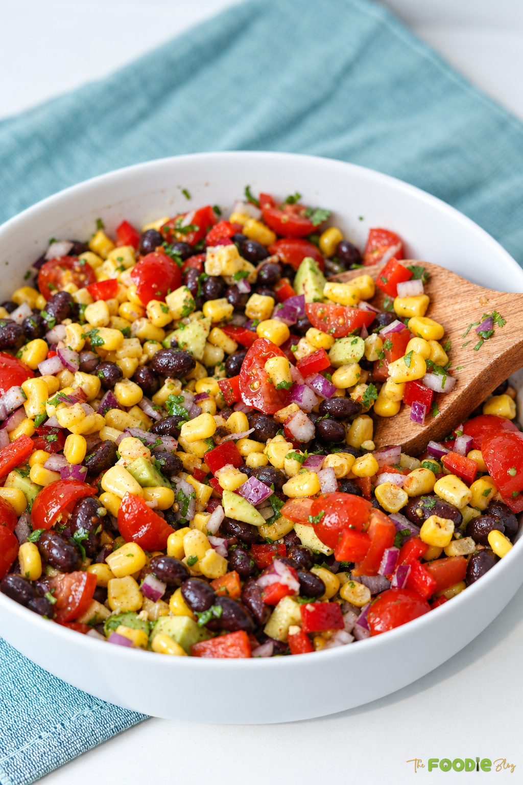 Finished cowboy caviar with black beans, corn, avocado, tomatoes, red onion, and cilantro.
