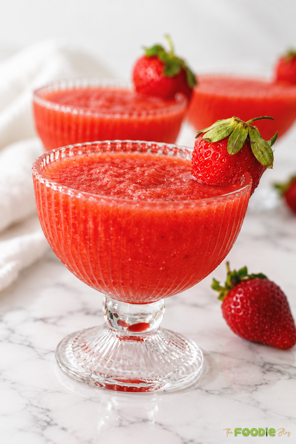 Close-up of a frozen strawberry daiquiri with thick strawberry texture and fresh berry garnish.