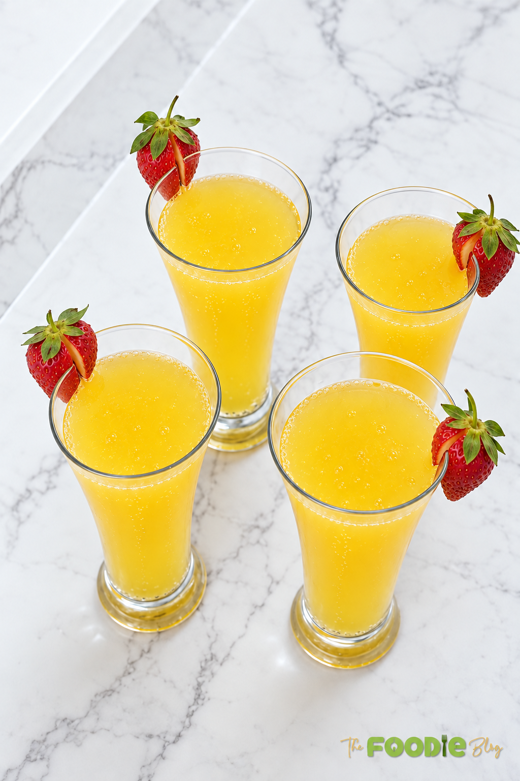 Four bubbly orange cocktails served in tall glasses with fresh strawberries.