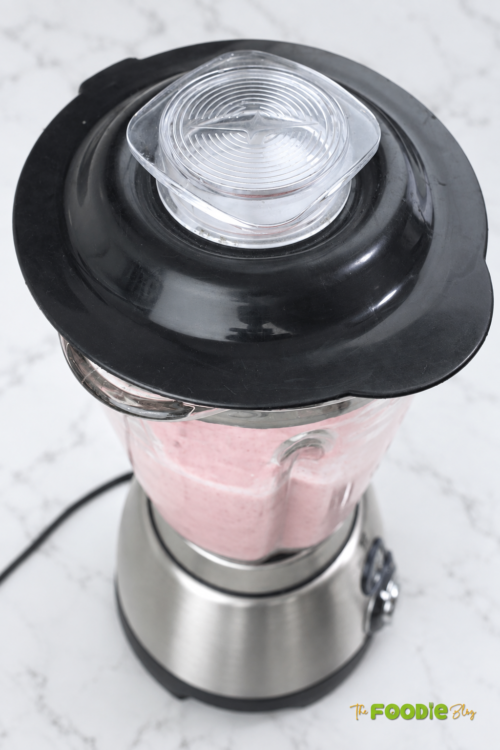 Strawberry banana smoothie blending until creamy and smooth in a countertop blender.
