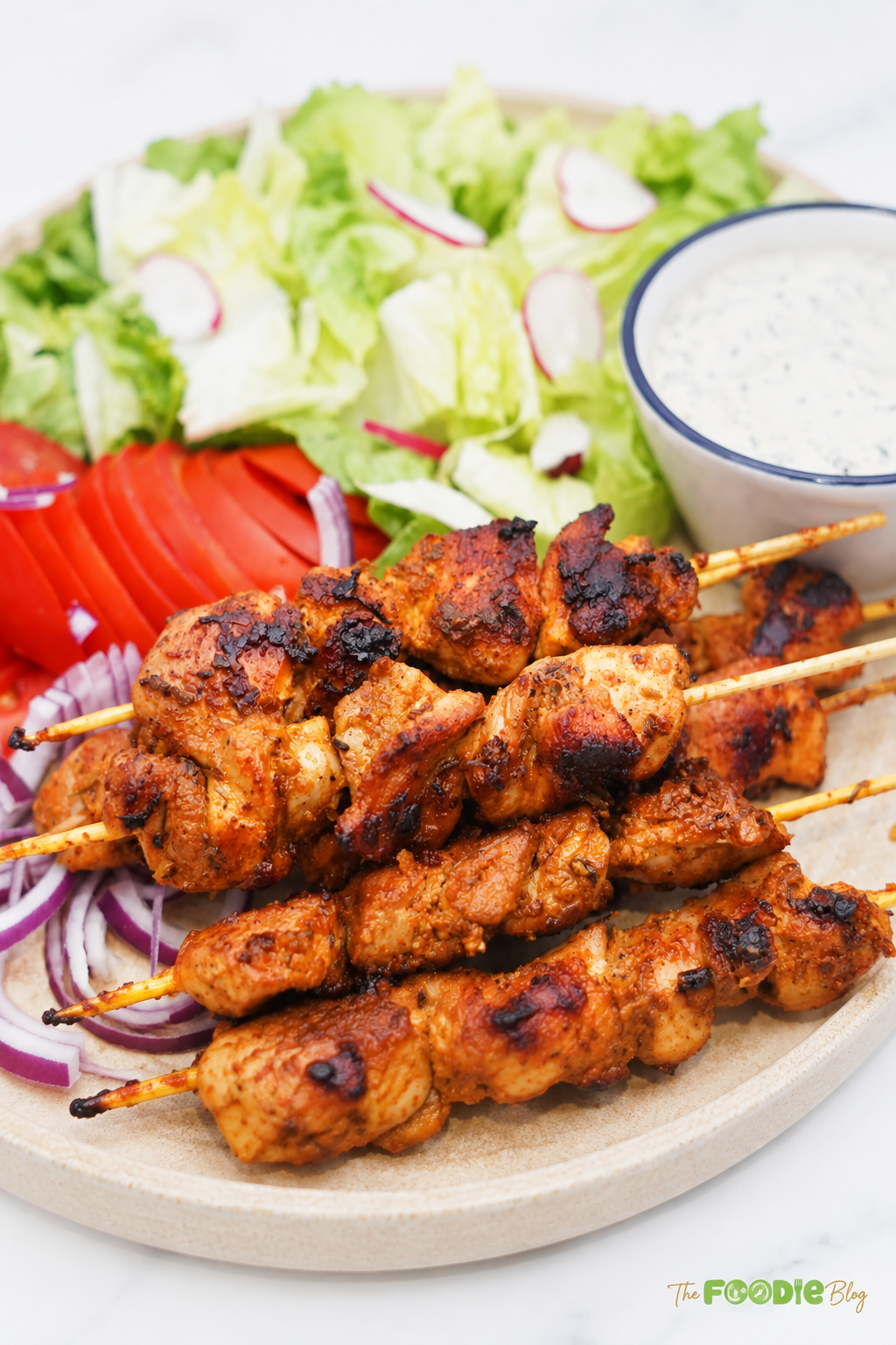 Close-up of juicy grilled chicken skewers with browned edges served beside salad and pita bread.