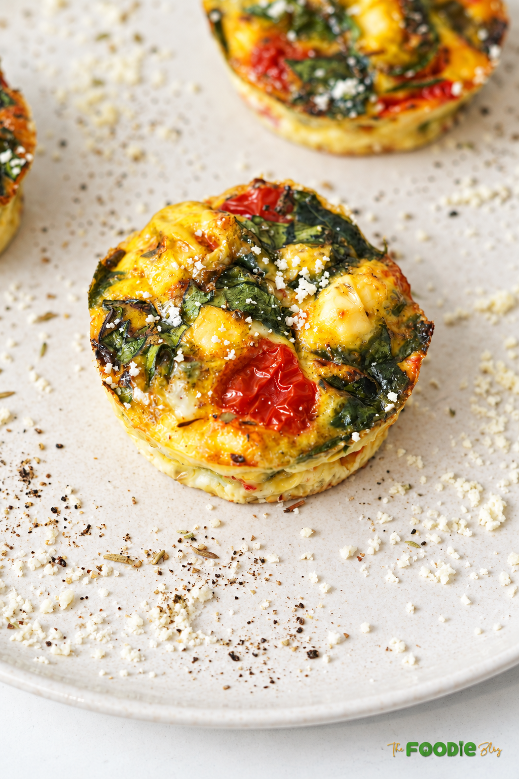Baked spinach tomato feta egg muffin served on a plate.