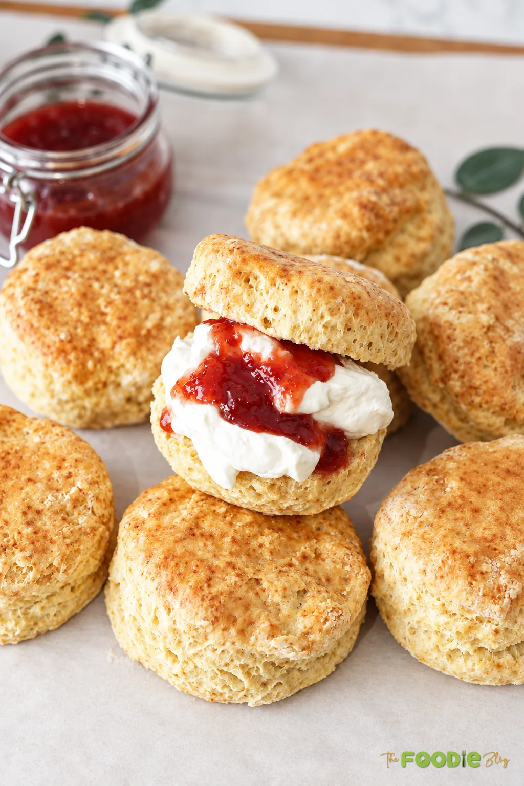 English scone filled with whipped cream and strawberry jam among freshly baked golden scones.