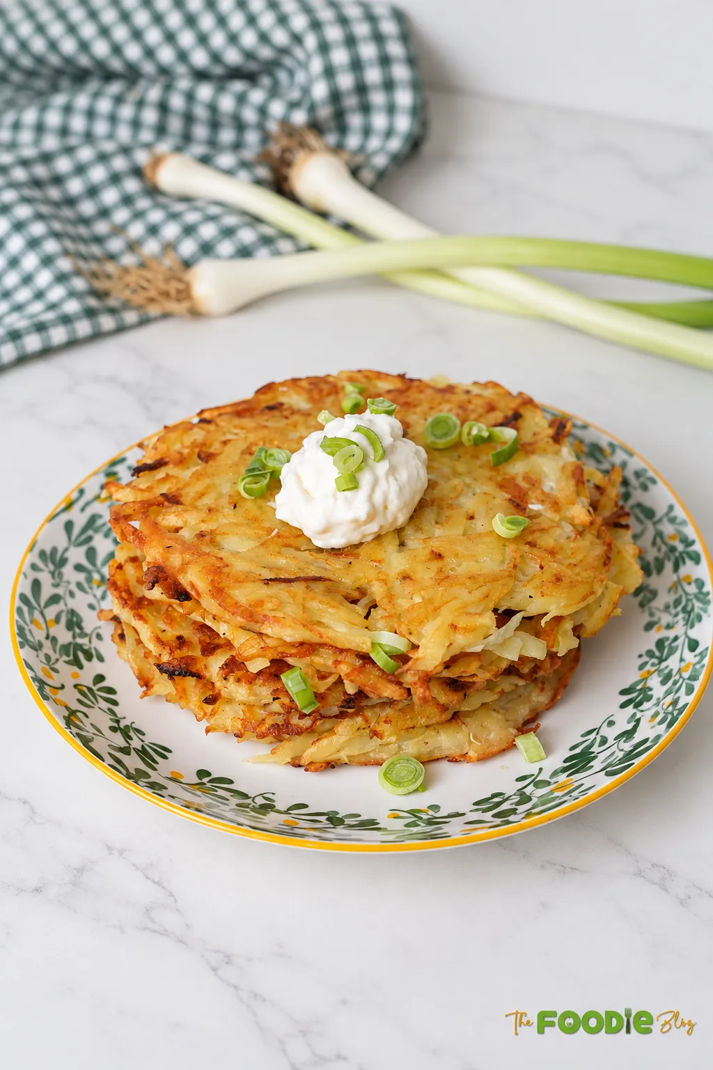 Golden German potato pancakes served with sour cream and green onions on a plate.