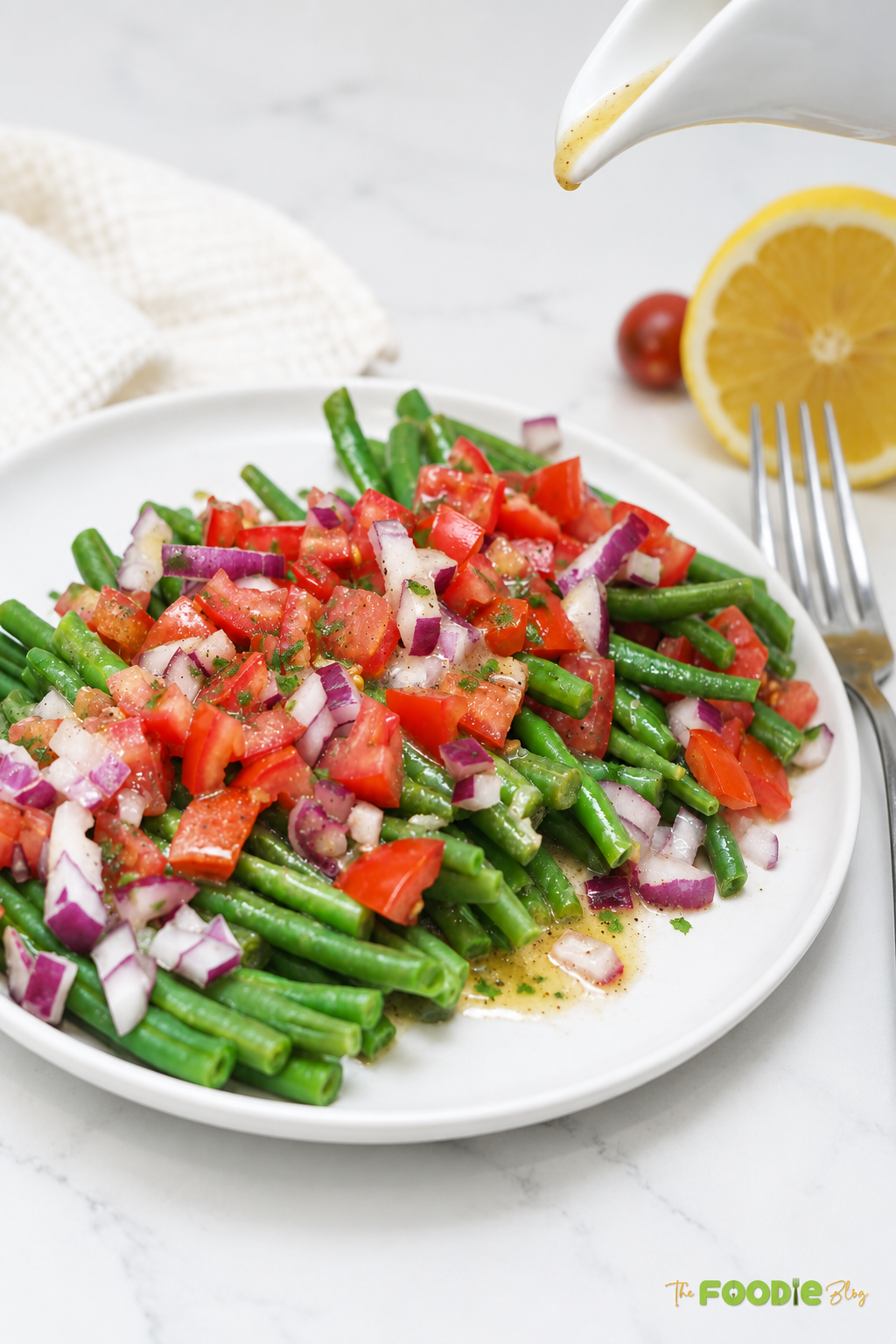 Lemon Dijon dressing being poured over green bean and tomato salad.