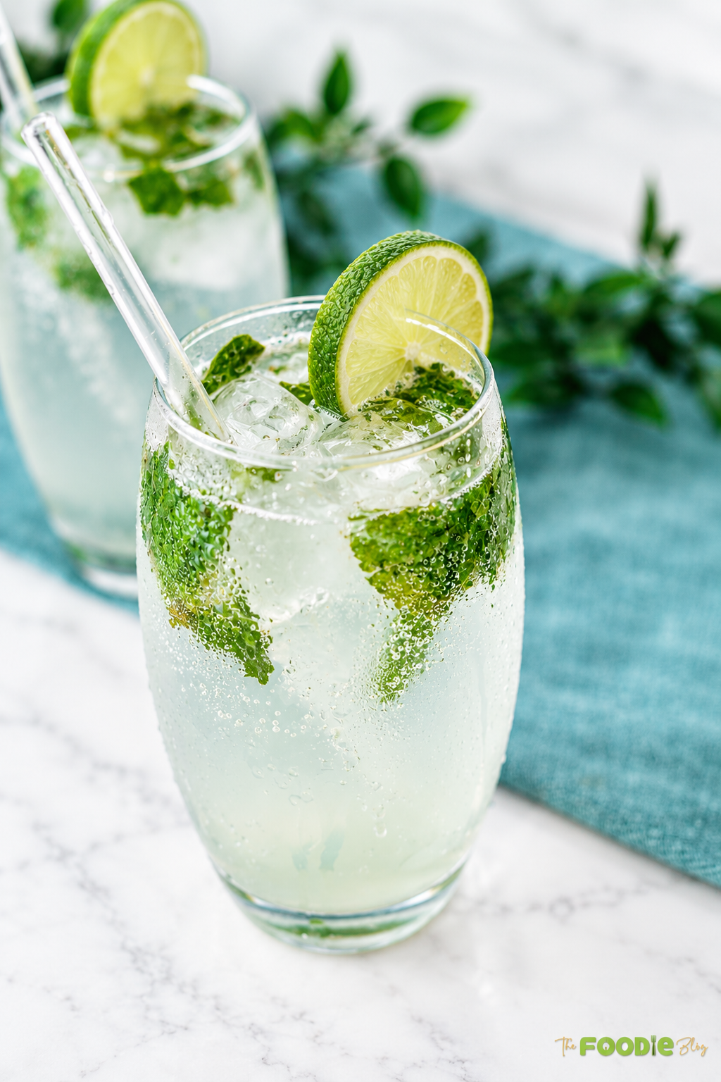 Close-up of a chilled mojito with fresh mint leaves, lime slice, crushed ice, and sparkling bubbles.