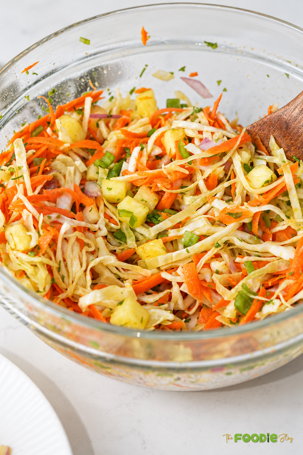 Close-up of pineapple coleslaw with shredded cabbage, carrots, pineapple chunks, red onion, jalapeños, and cilantro.