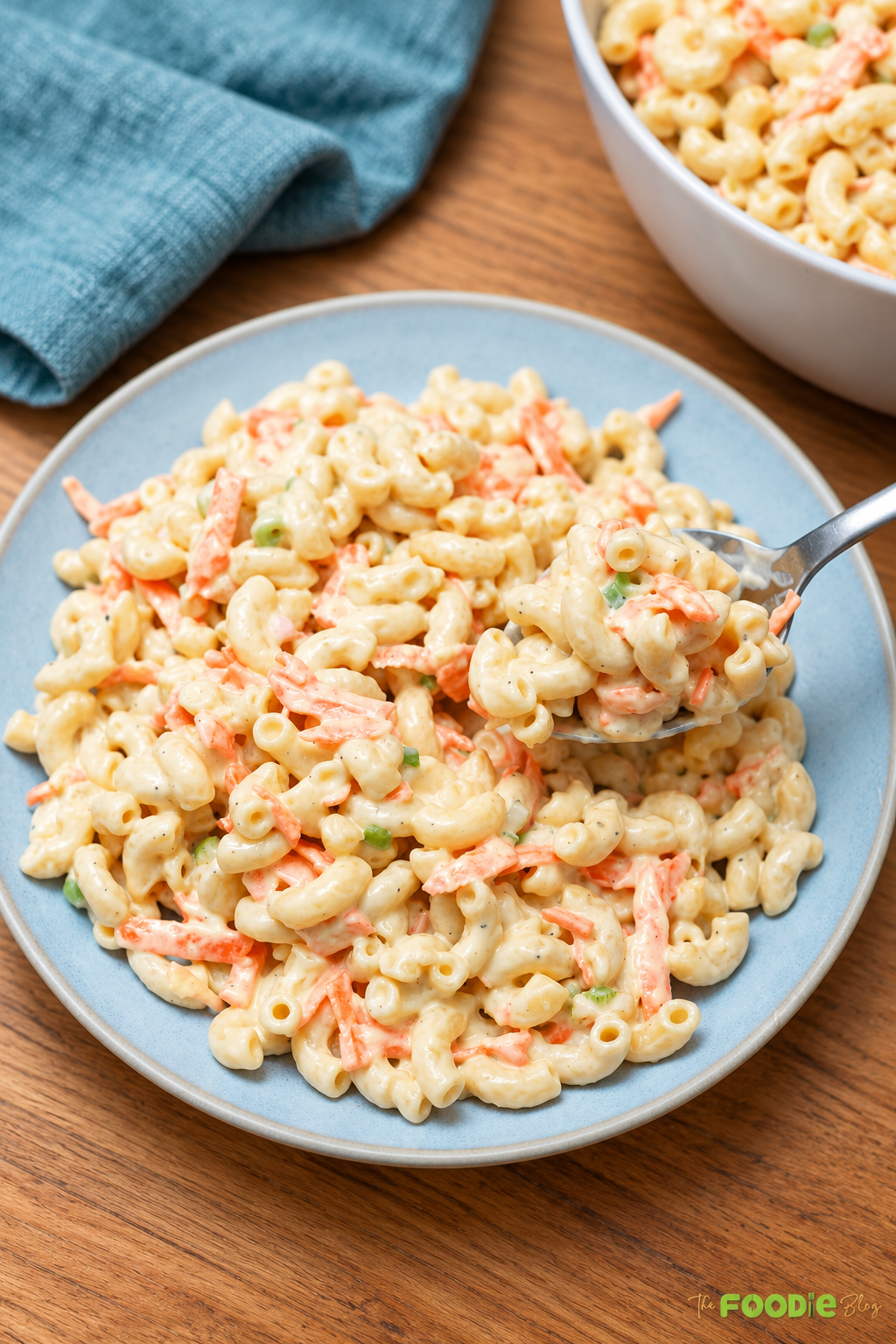 Creamy Hawaiian macaroni salad served on a blue plate with a spoonful lifted.