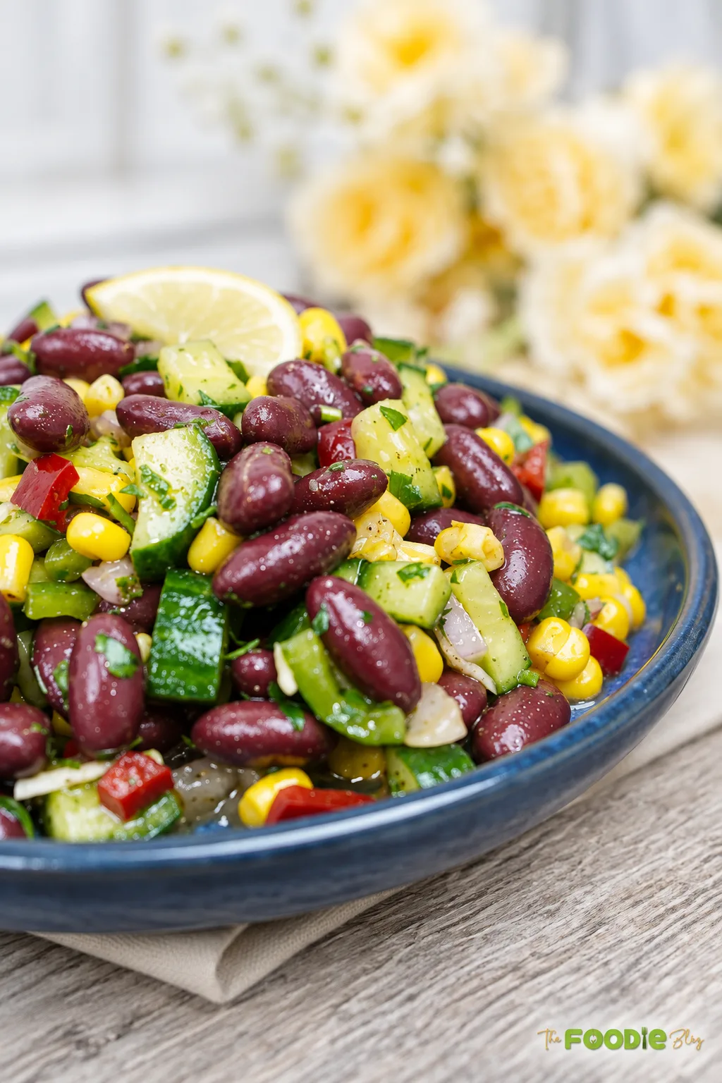 Close-up of red bean salad with kidney beans, corn, cucumber, red pepper, onion, parsley, and lemon.