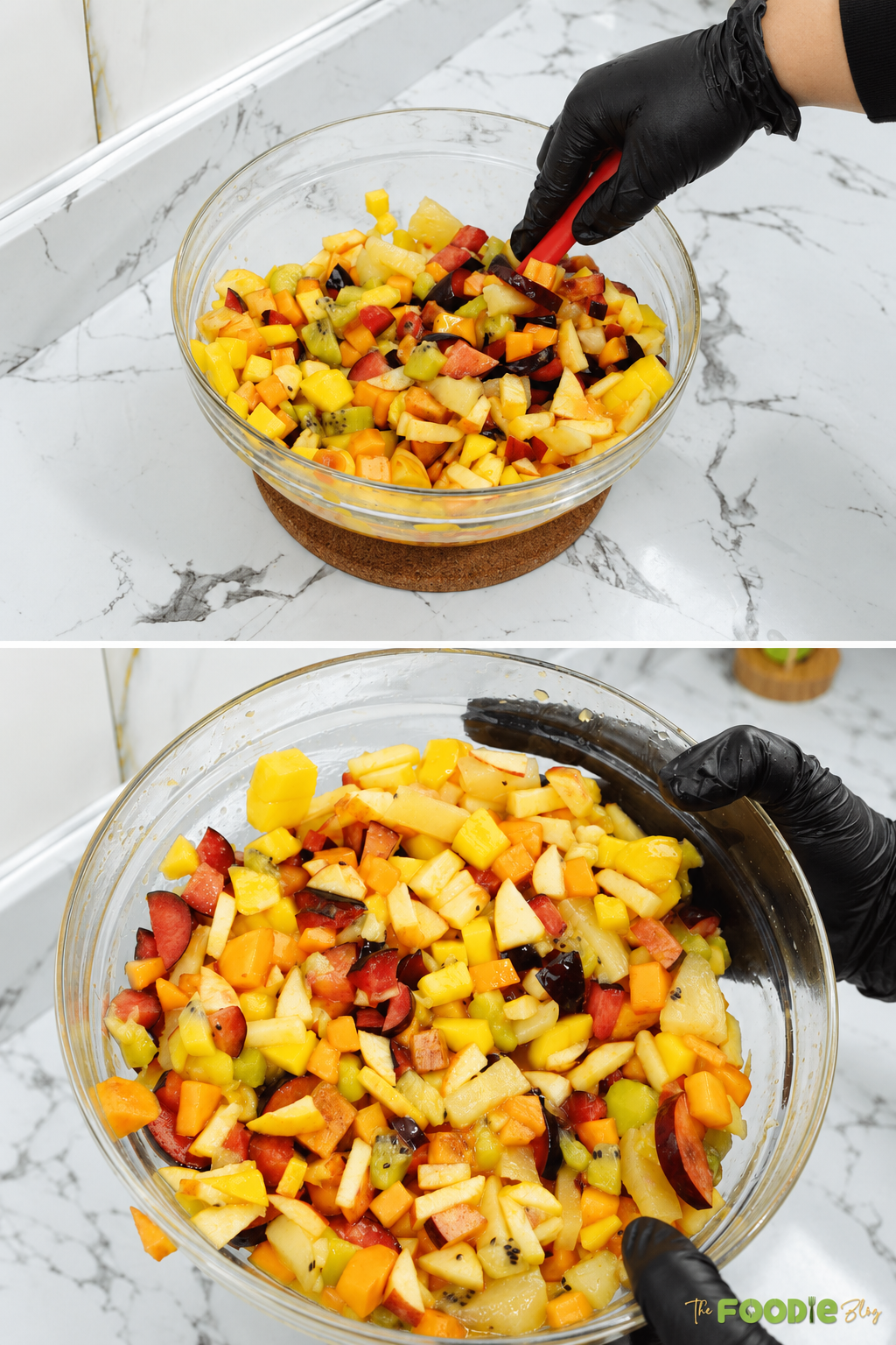 Mixed fruit salad with pineapple, mango, kiwi, apples, plums, and persimmons being tossed in a glass bowl.