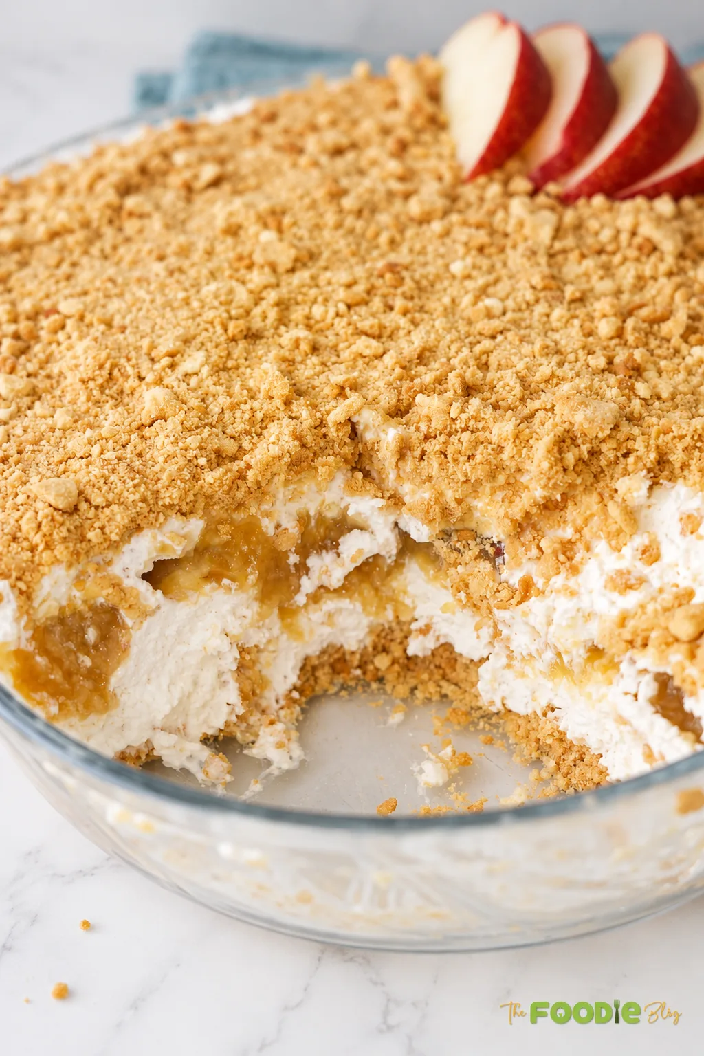 Close-up of layered peach dessert showing creamy filling, peach mixture, and crunchy biscuit crumb topping.