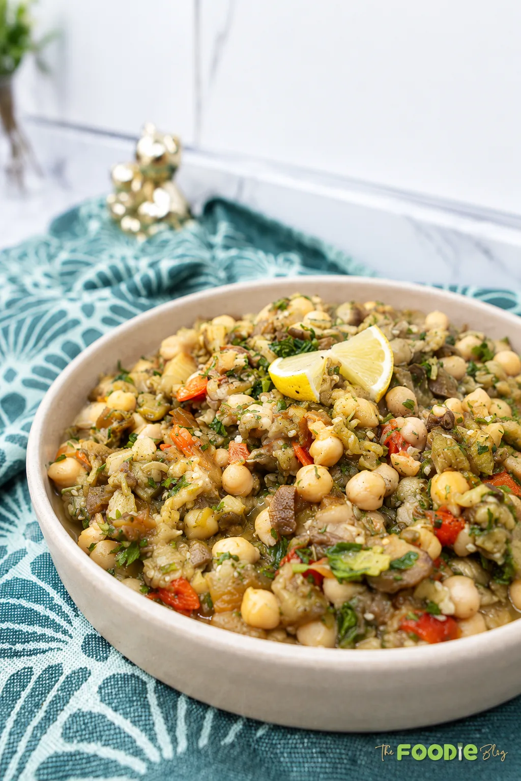Roasted eggplant chickpea salad topped with lemon wedges and fresh parsley.