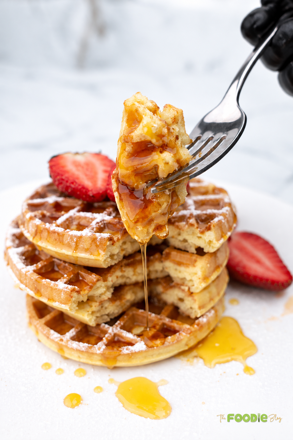 Close-up of a fluffy waffle bite on a fork dripping with maple syrup
Title: Fluffy Waffle Bite